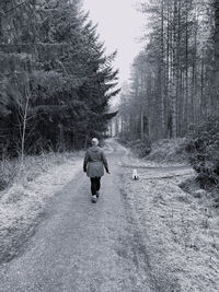 Rear view of woman walking on road during winter