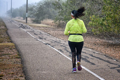 Rear view of woman running on road