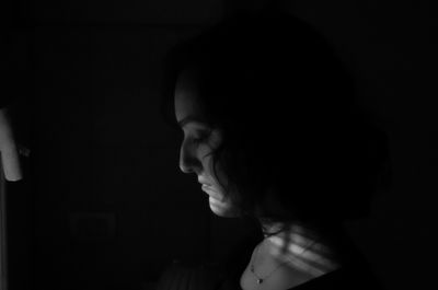 Side view of young woman against black background