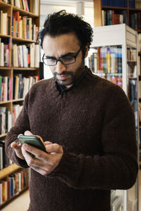 Man using phone while standing in library