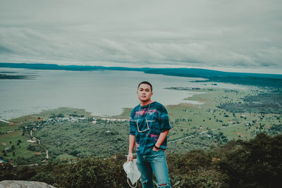 Young man standing on mountain against sky