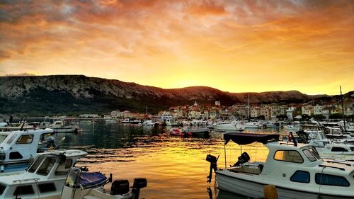 Boats moored at harbor during sunset