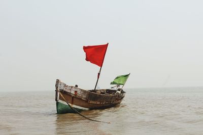 Flag on boat in sea against clear sky