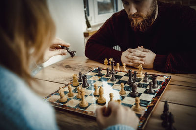 Couple playing chess on table at home