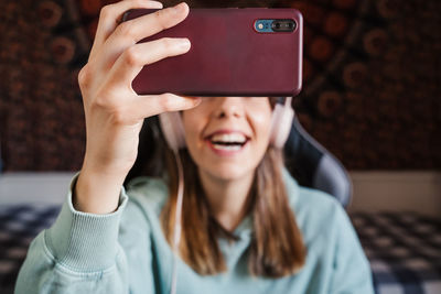 Smiling young woman video conferencing over mobile phone