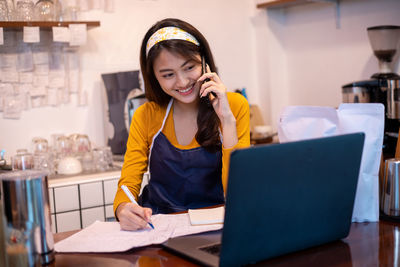 Portrait of young woman using laptop at table