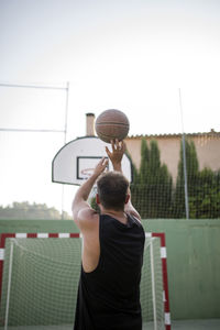 Rear view of man playing with ball against sky