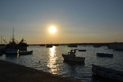 Boats in sea at sunset