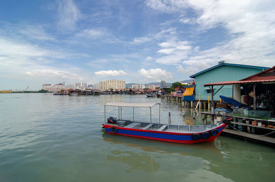 Fishing boats moored at harbor against sky