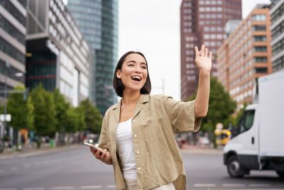 Portrait of young woman standing in city