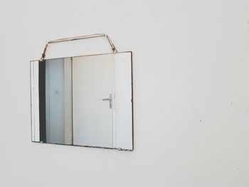 Reflection of closed door in mirror hanging on wall