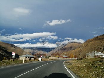 Road leading towards mountains against sky