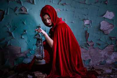 Midsection of woman holding red while standing against wall