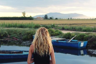 Rear view of woman standing on lake against sky