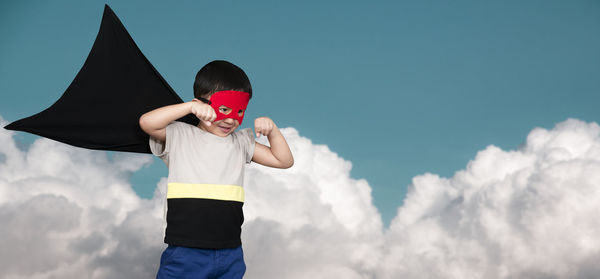 Low angle view of boy standing against sky