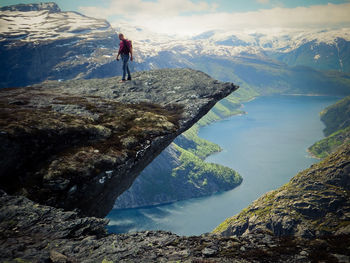 Hiker walking on cliff against sky