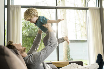 Happy father playing with son on sofa at home