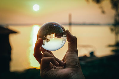 Midsection of man holding crystal ball with reflection