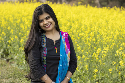 A pretty indian woman with smiling face looking at camera in mustard field