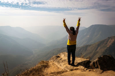 Woman standing on mountain against sky