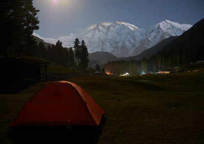 Tent on field by mountains against sky at night