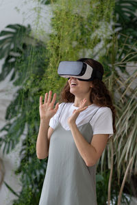 Overjoyed young woman spending leisure time in virtual reality while relaxing at home garden