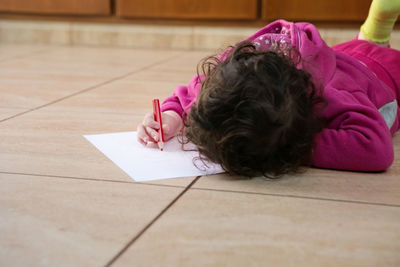 Rear view of girl sitting on tiled floor