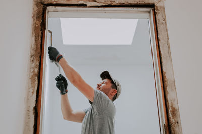 A man working with a crowbar in a doorway.
