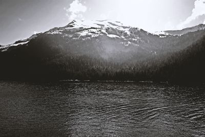 Scenic view of lake by snowcapped mountains against sky