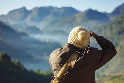 Rear view of man standing on mountain against sky