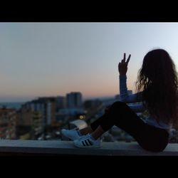 Midsection of woman in city against sky during sunset