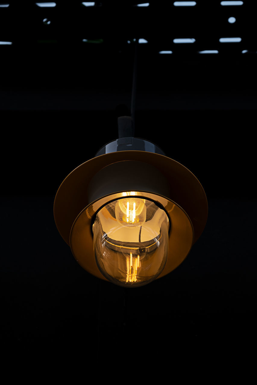 CLOSE-UP OF ILLUMINATED LIGHT BULB HANGING FROM CEILING