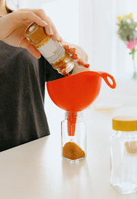 A girl pours spice seasoning from a bag into a jar.