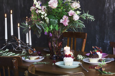The beautiful festive table with rustic bouquet, cupcakes and space