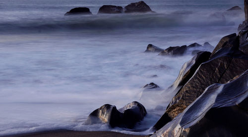 Rocks in sea against sky during winter