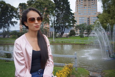 Woman wearing sunglasses while sitting against fountain