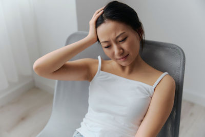 Young woman with headache sitting on chair