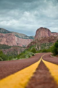 Road leading towards rocky mountains against sky