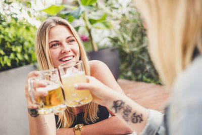 Young woman toasting drinks sitting at table