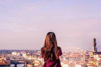 Rear view of woman with cityscape against sky
