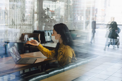Woman using mobile phone while sitting in restaurant