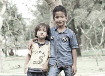 Portrait of boy standing with brother at park