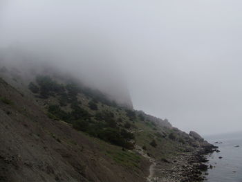 Scenic view of mountains in foggy weather against sky