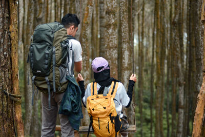 Couple climbers in the pine forest playing on the swing