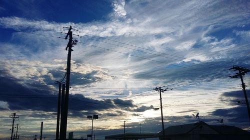 Low angle view of silhouette electricity pylon against sky