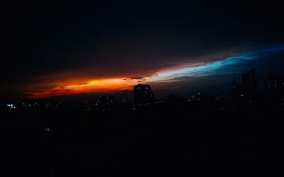 Silhouette buildings against sky at night