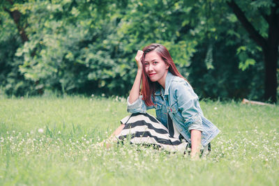 Portrait of young woman on grass in field