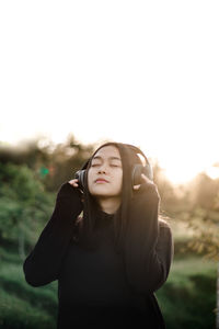 Beautiful young woman standing against sky