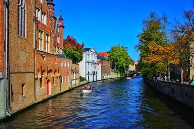 Canal amidst buildings in city against clear blue sky