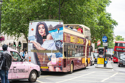 Portrait of vehicles on road against trees in city